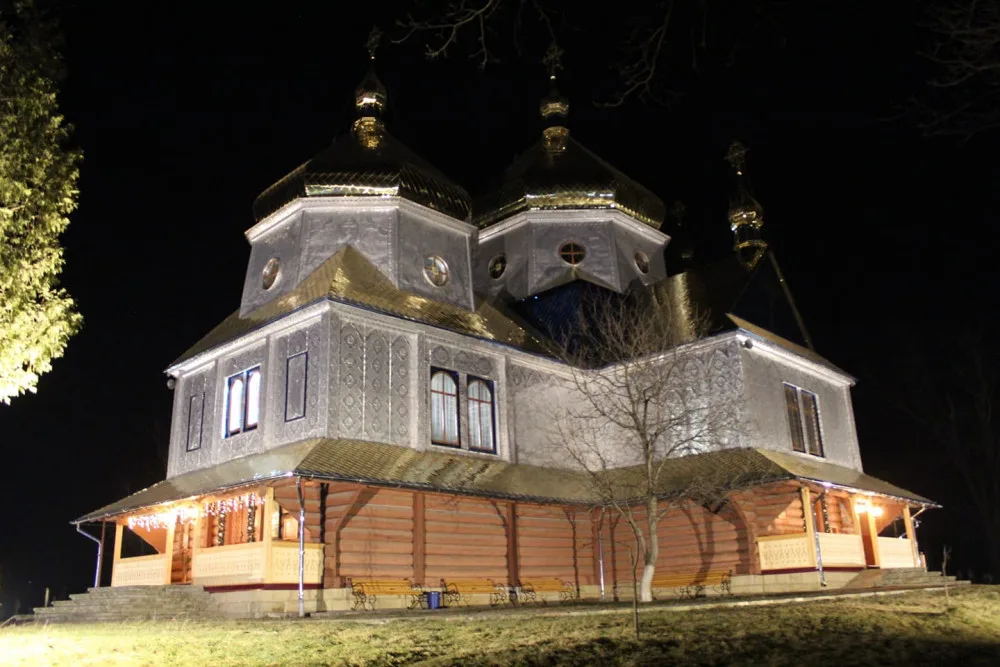 Дерев’яна церква з золотими куполами вночі