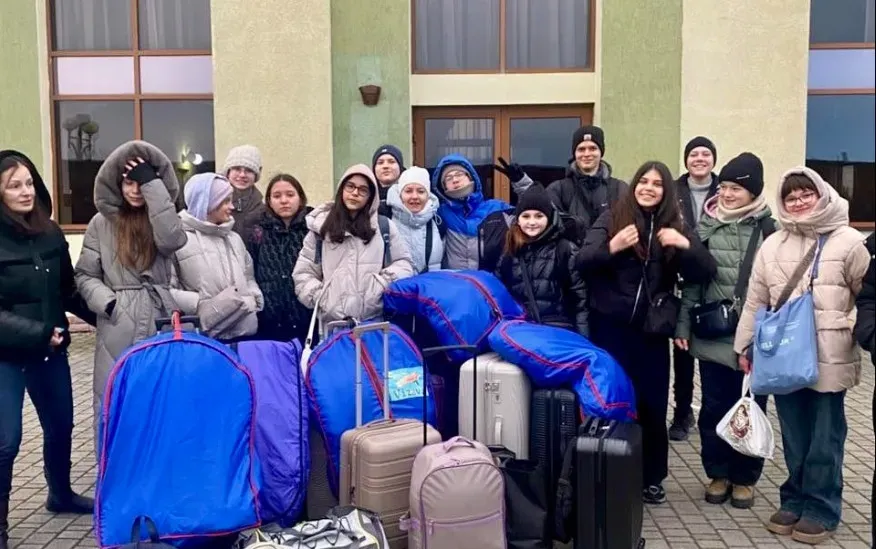 Група людей з багажем перед будівлею