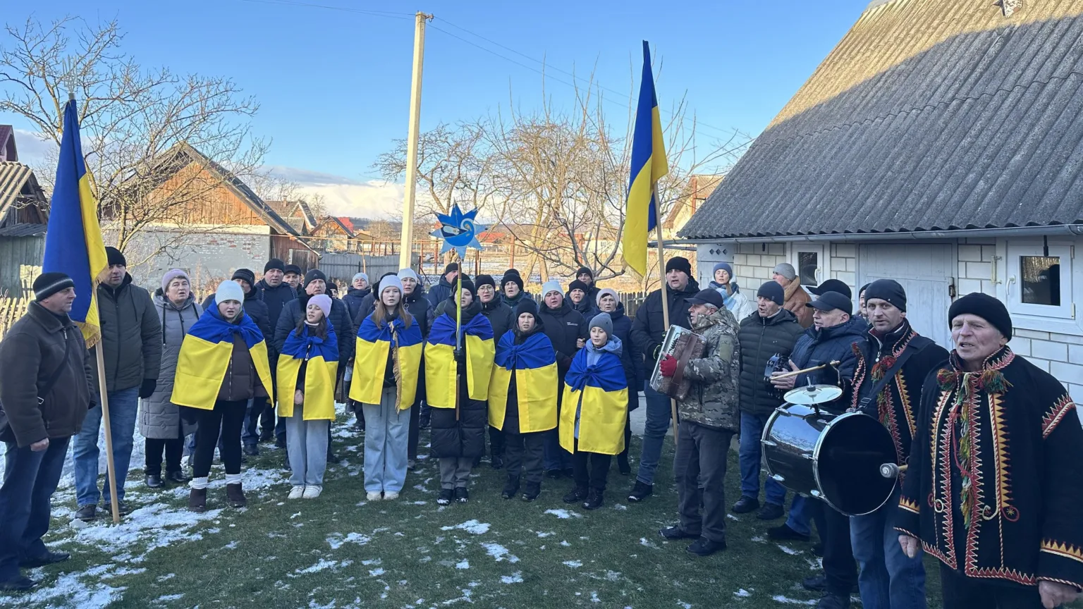 Люди з українськими прапорами співають на вулиці