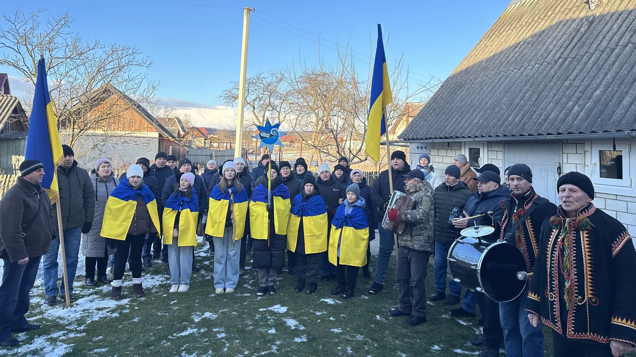 Люди з українськими прапорами співають на вулиці