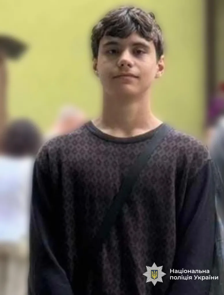 Підліток у темній кофті стоїть на вулиці