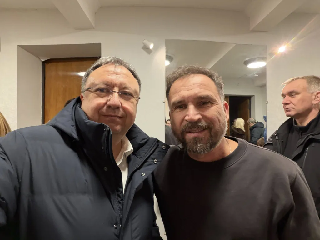 Двоє чоловіків посміхаються на фото в приміщенні