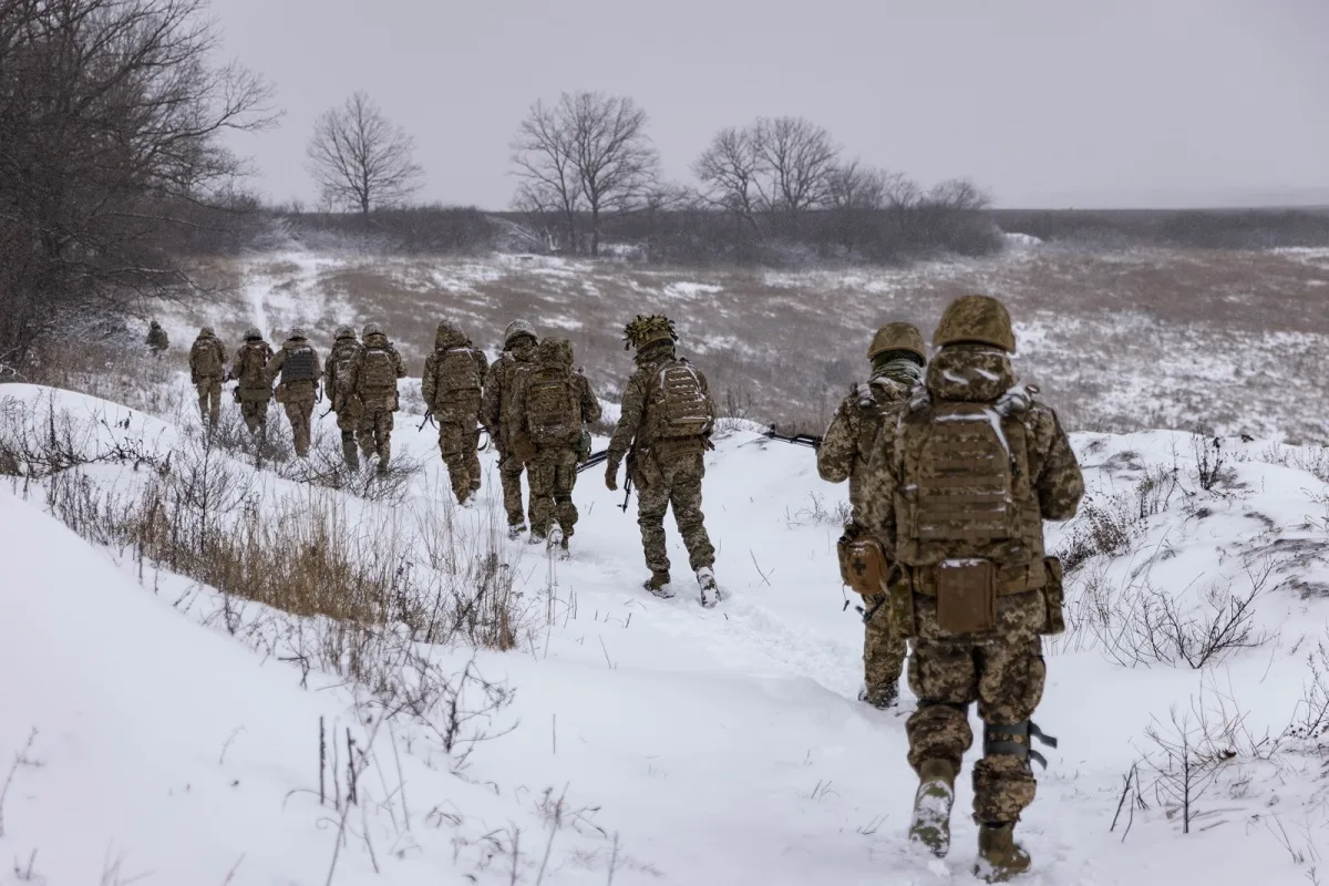 Військові йдуть зимовим полем у камуфляжі
