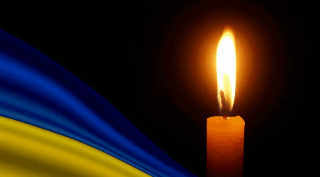 Свічка та прапор України на чорному тлі