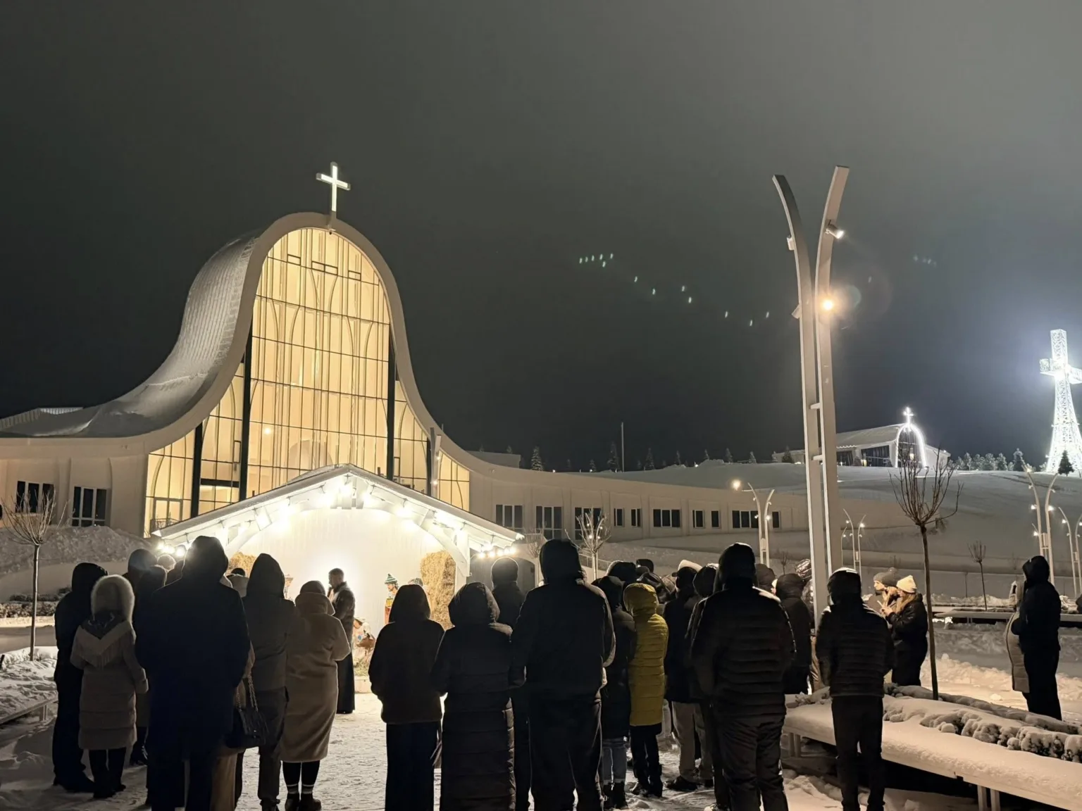 Люди біля освітленої церкви взимку вночі