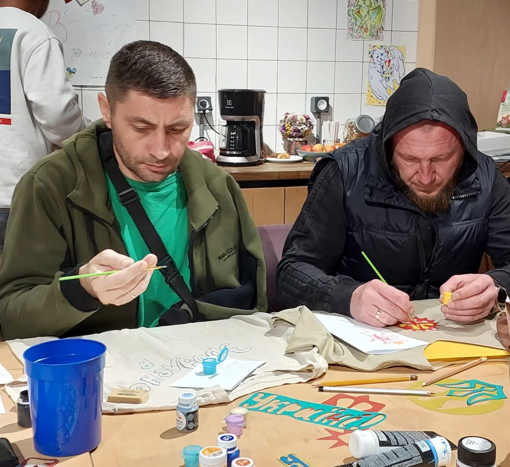 Двоє чоловіків малюють пензлями на футболках