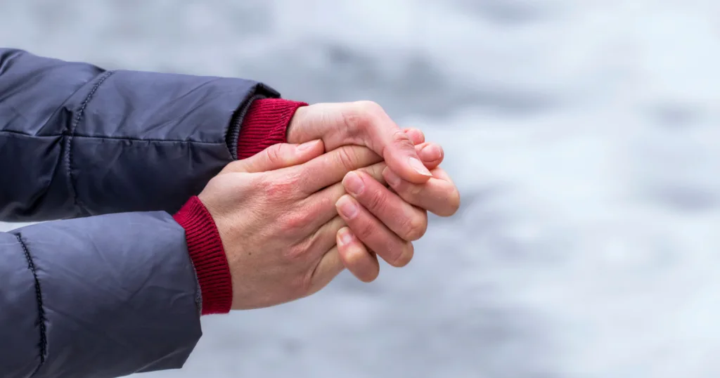 Людина гріє руки на холоді