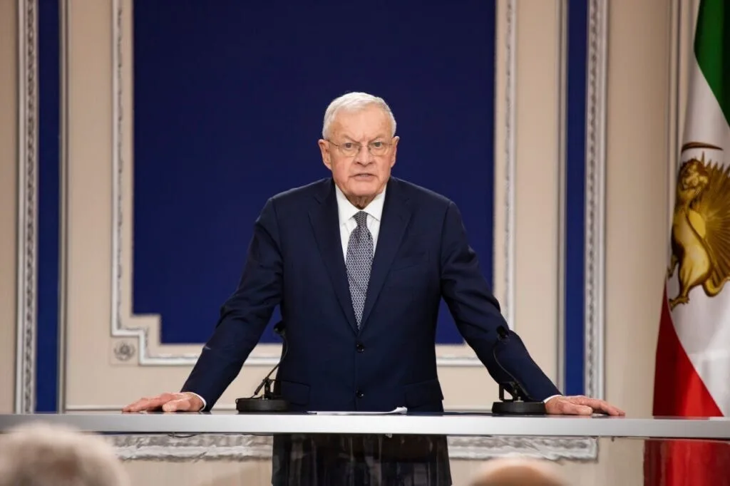 Чоловік у костюмі виступає за трибуною