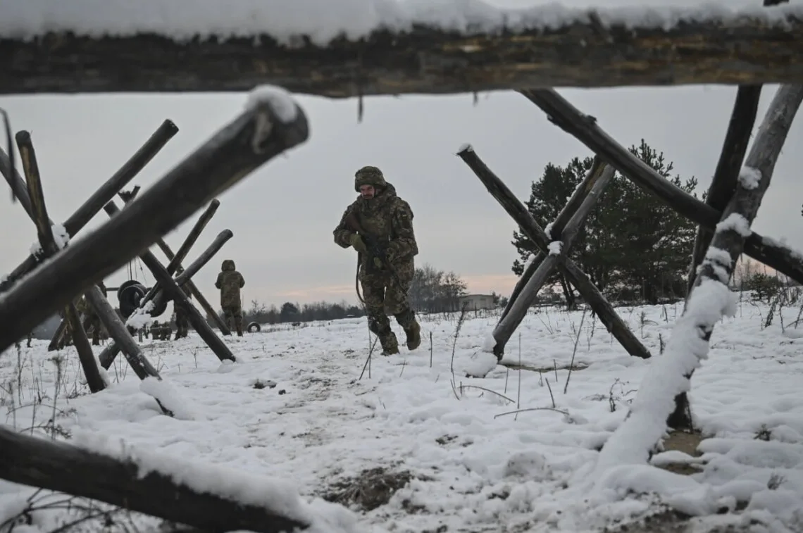 Військові йдуть через засніжене поле з укріпленнями