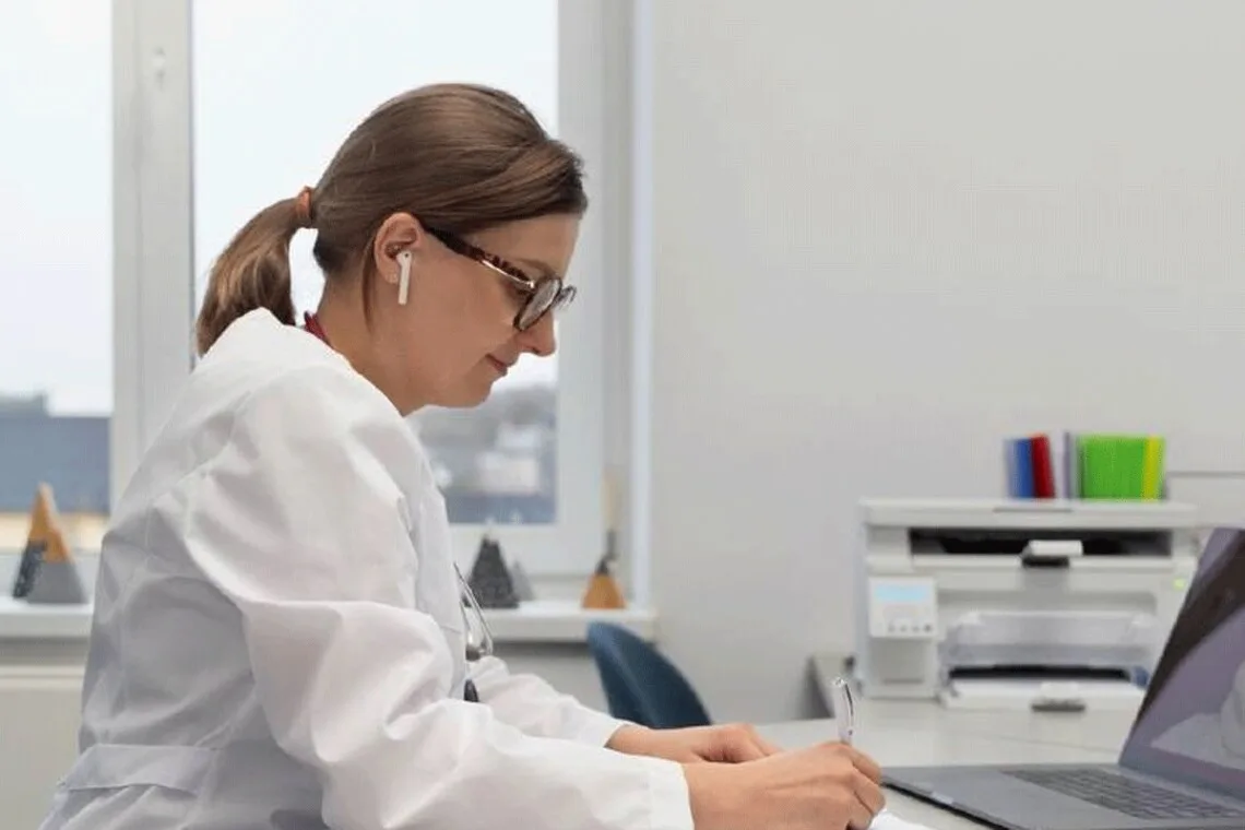 Медик працює за ноутбуком у кабінеті