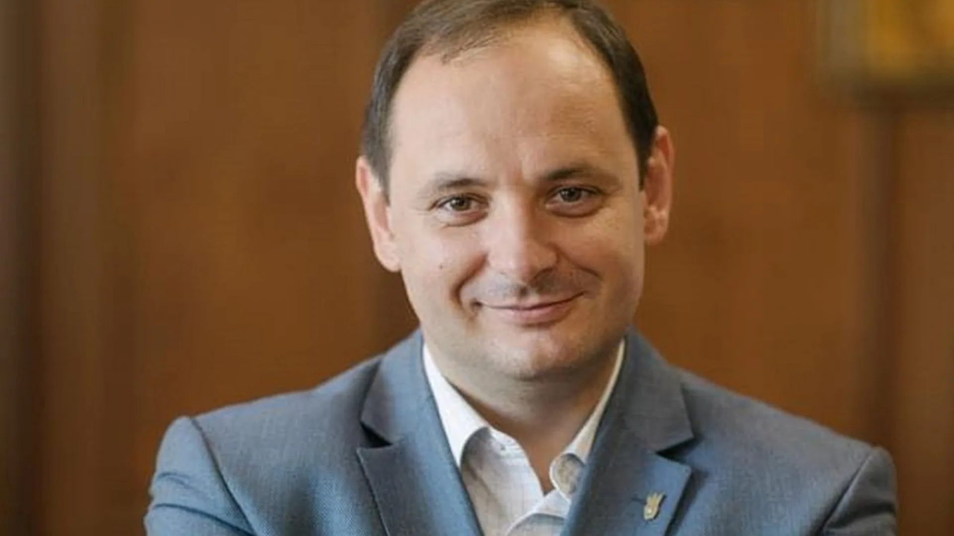 Чоловік у костюмі посміхається перед камерою