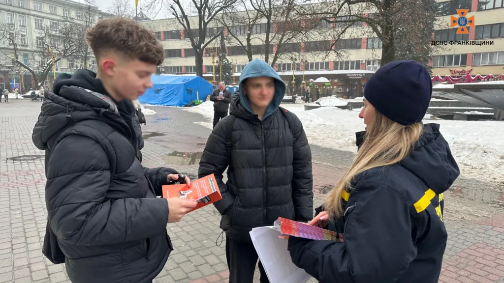 Рятувальниця роздає інформаційні листівки перехожим на вулиці