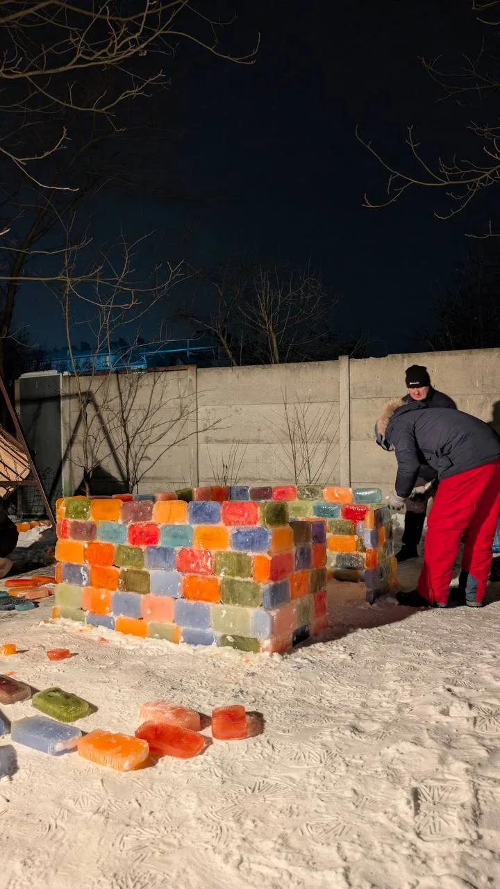 Люди будують кольорову крижану стіну взимку