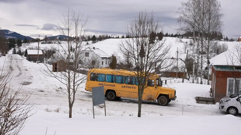 Жовтий шкільний автобус у засніженому селі