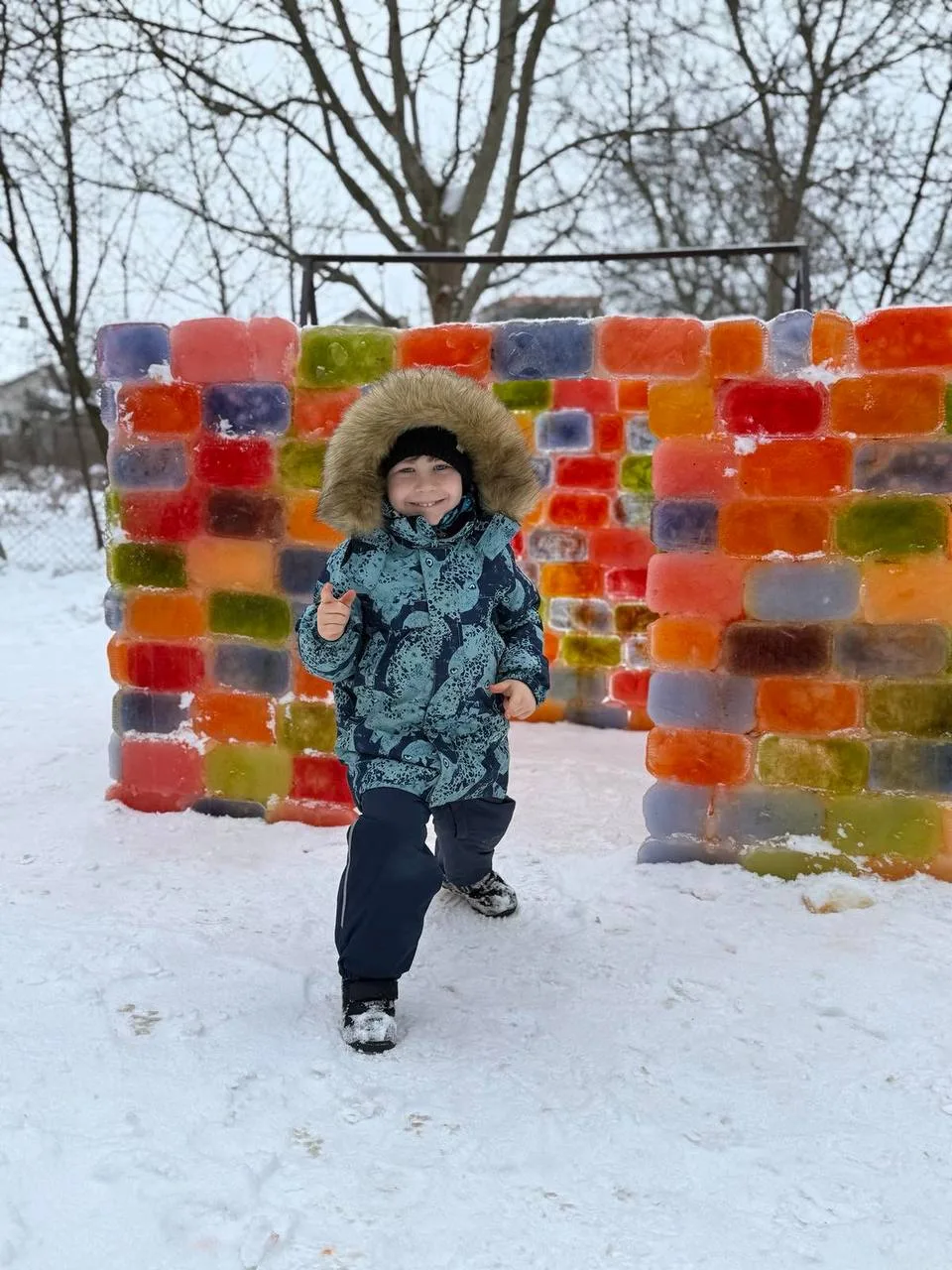 Дитина грає біля кольорової крижаною стіни