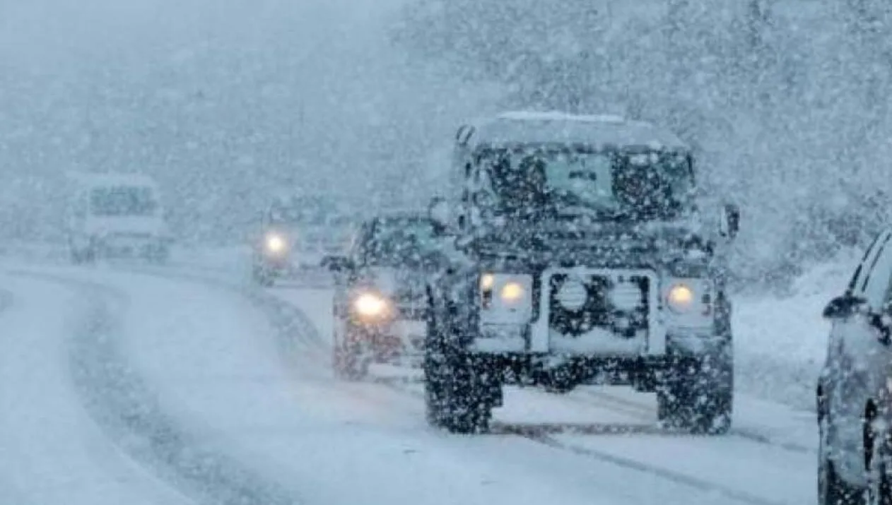 Автомобілі їдуть дорогою під час сильного снігопаду