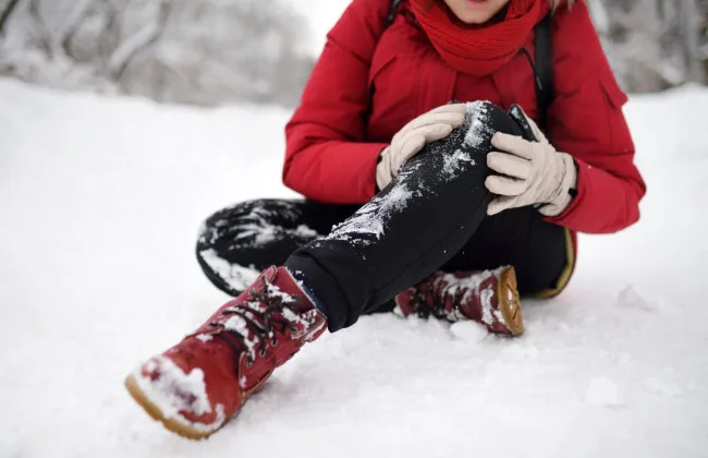 Людина впала на снігу та тримається за коліно