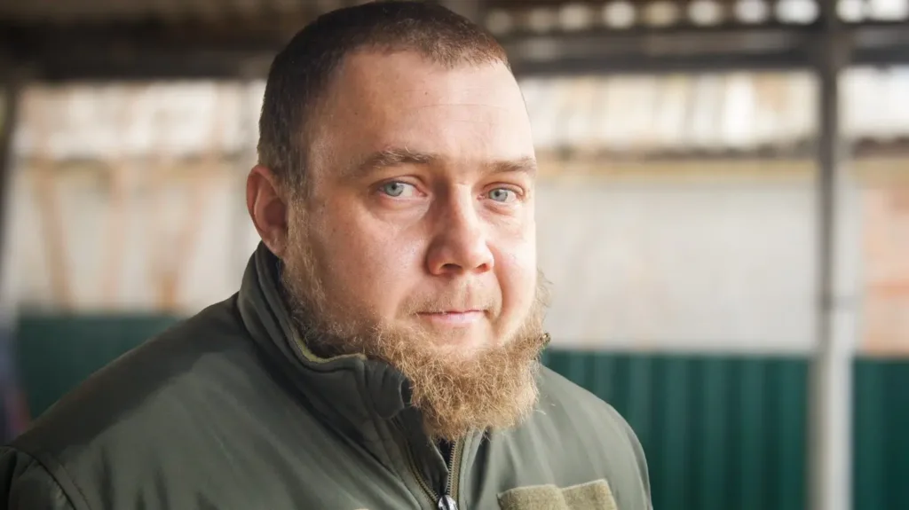 Чоловік з бородою у зеленій куртці