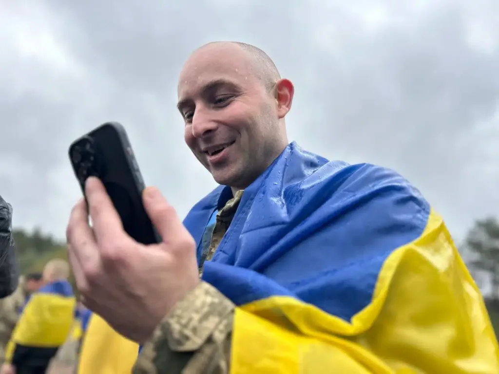 Український військовий з прапором дивиться на телефон