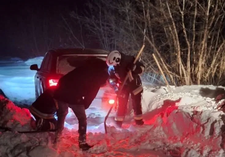 Рятувальники відкопують авто зі снігу вночі