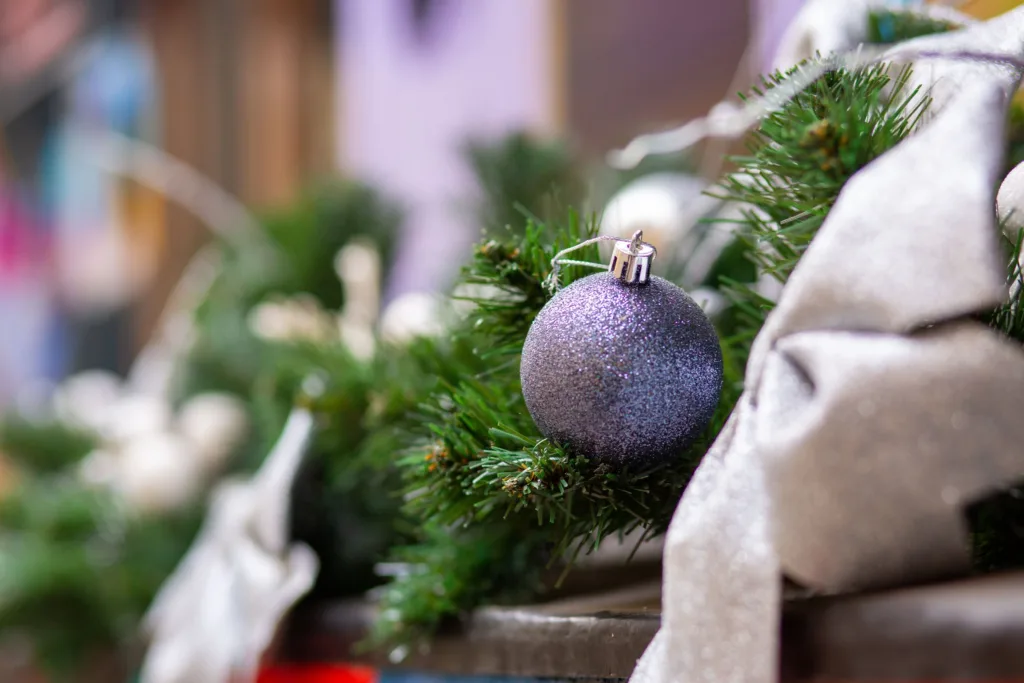 Фіолетова новорічна кулька на зеленій гілці