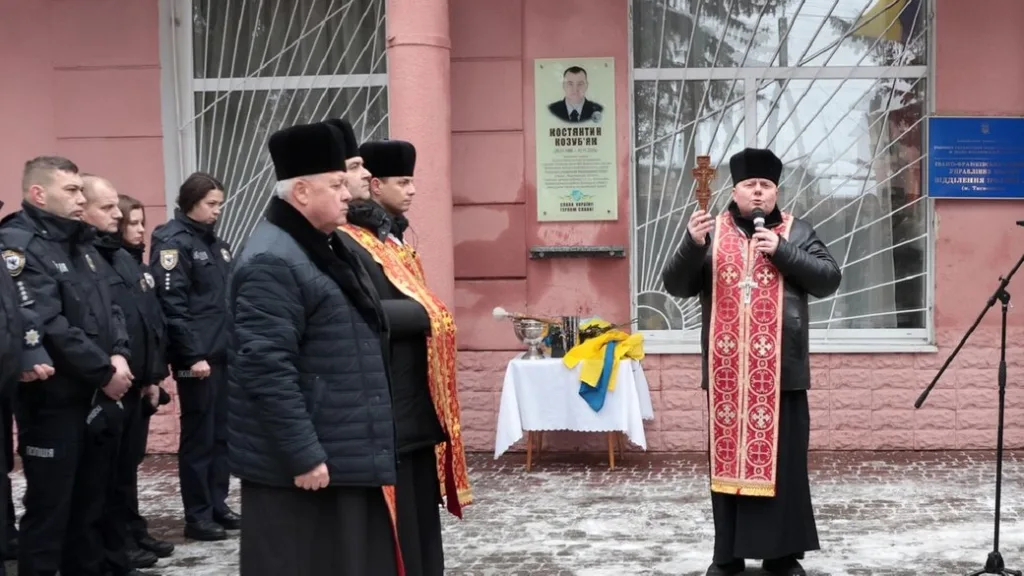 Священник благословляє поліцейських перед будівлею