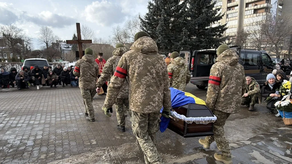 Військові несуть труну, накриту українським прапором