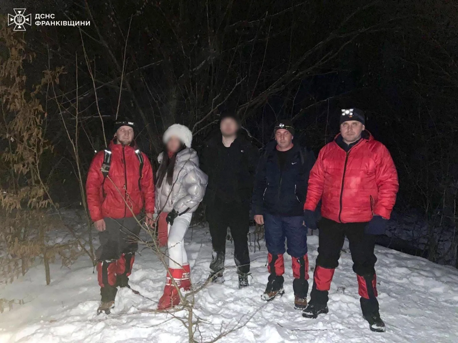 Рятувальники з людьми в зимовому лісі вночі