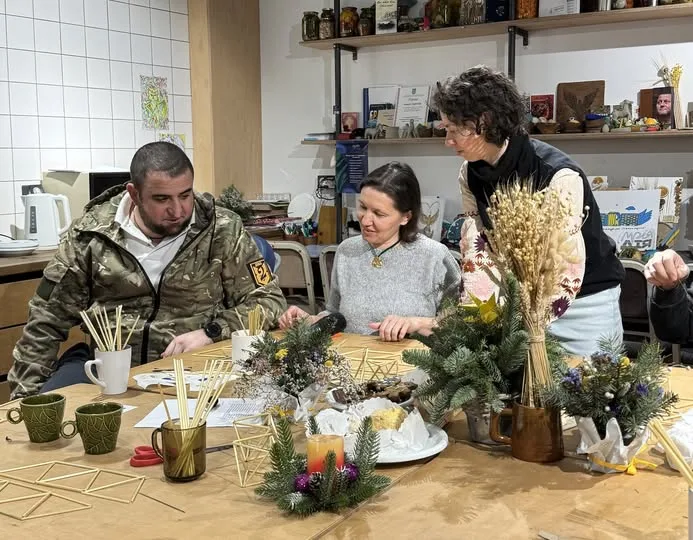 Люди виготовляють солом'яні прикраси за великим столом