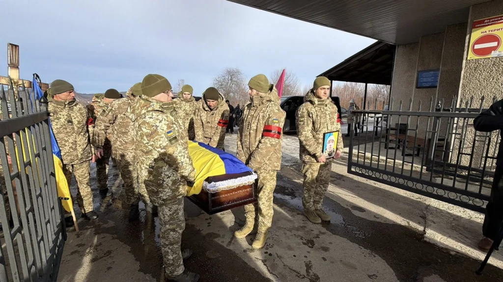 Військові несуть труну, накриту українським прапором