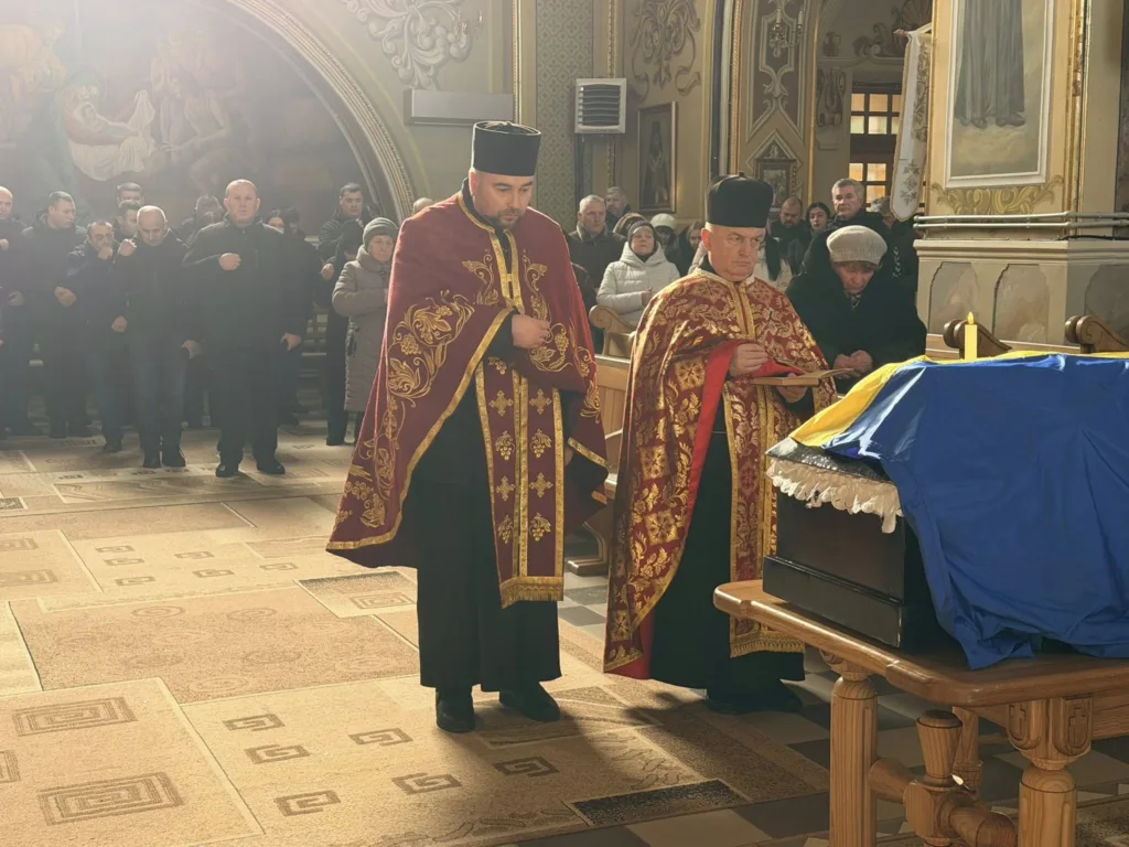 Священники моляться біля труни в церкві