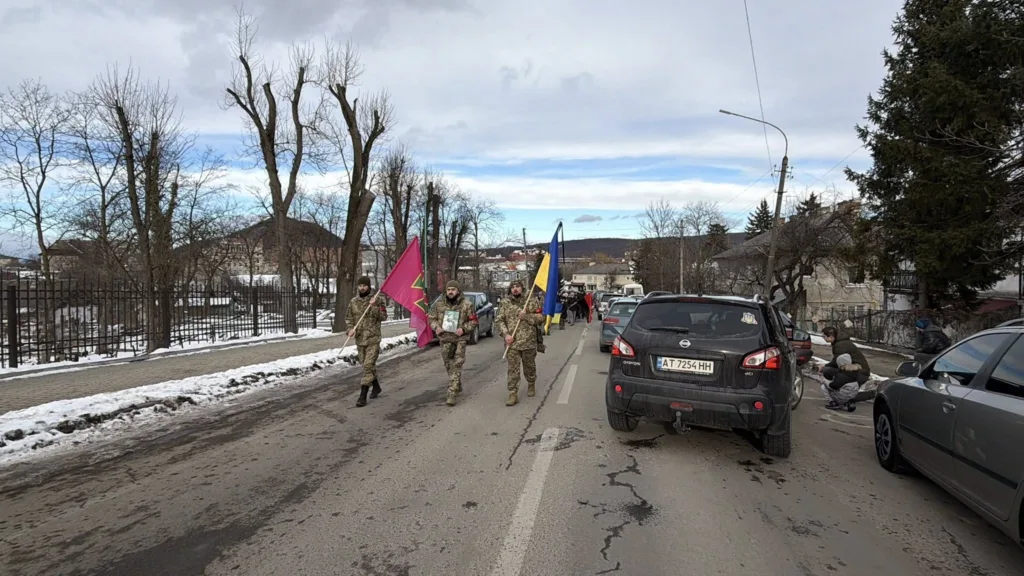 Військові з прапорами йдуть зимовою вулицею