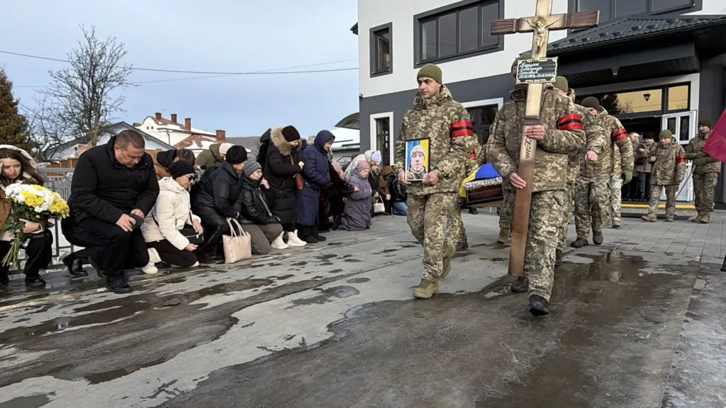 Прощання із загиблим військовим, люди на колінах