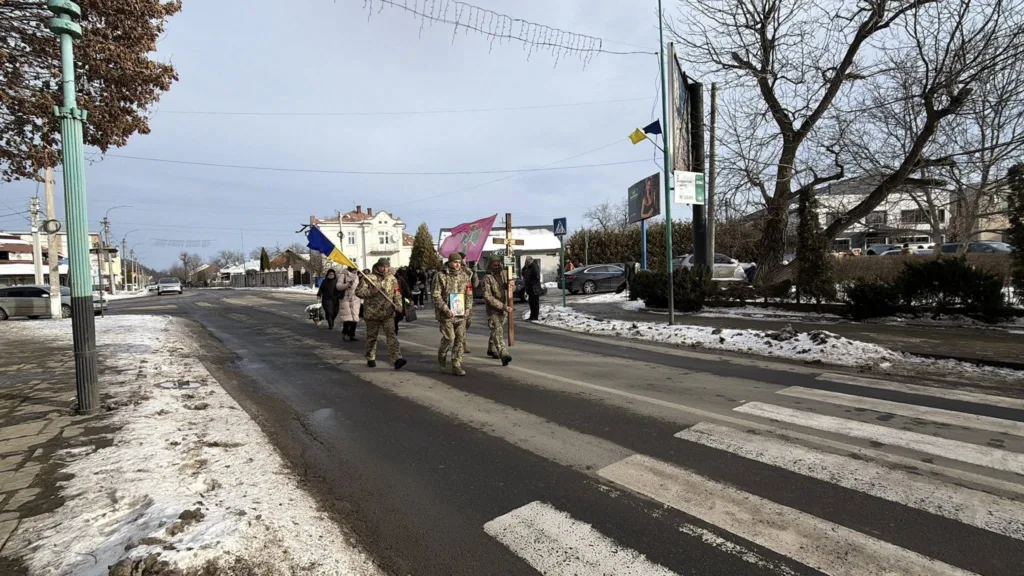 Військові з прапорами йдуть зимовою вулицею