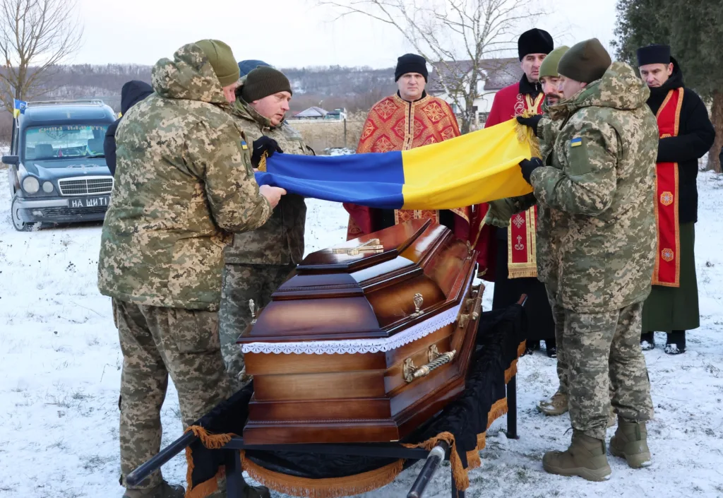 Військові накривають труну українським прапором