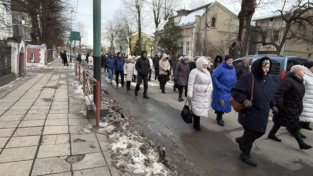 Люди йдуть зимовою вулицею у теплих куртках