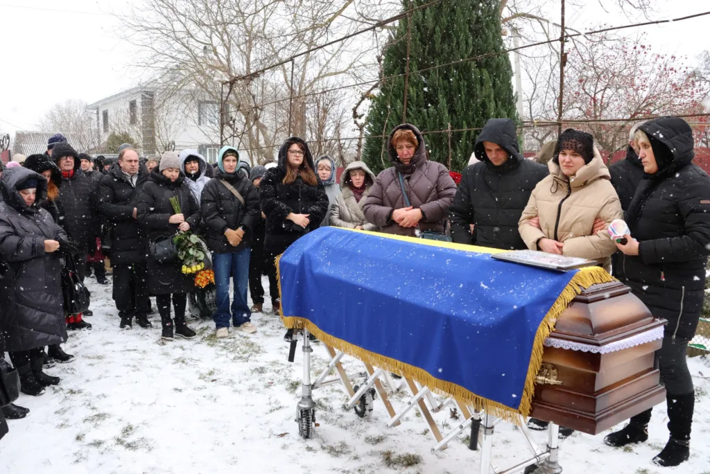 Похоронна церемонія на снігу з труною під прапором