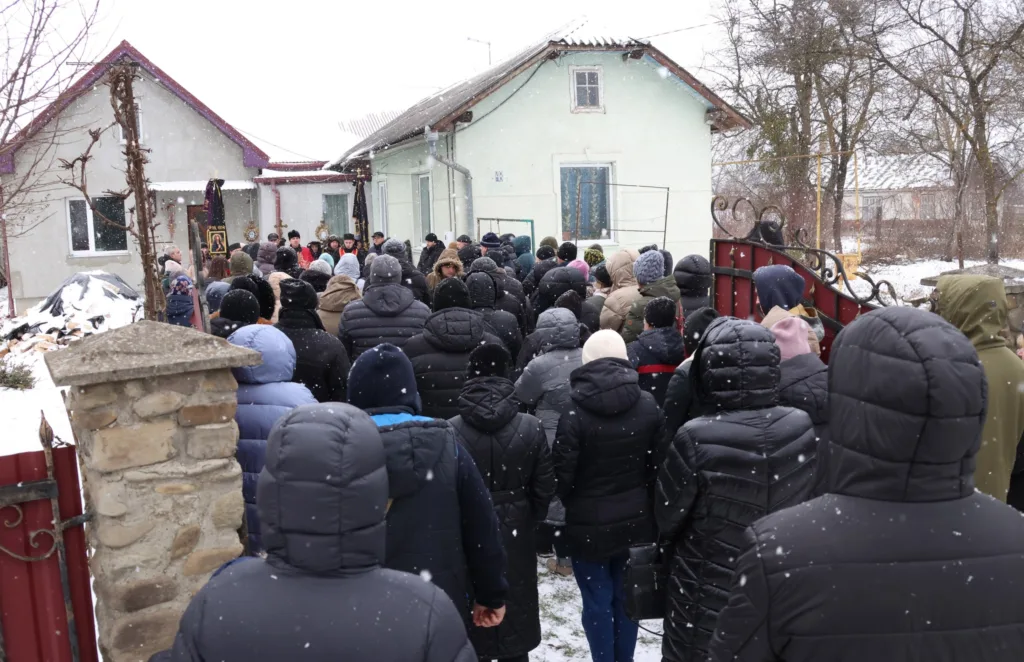 Люди зібралися біля будинку взимку під снігом