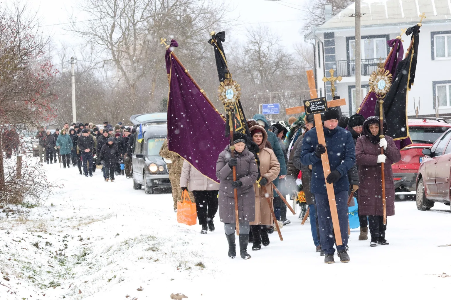 Похоронна процесія йде засніженою вулицею села