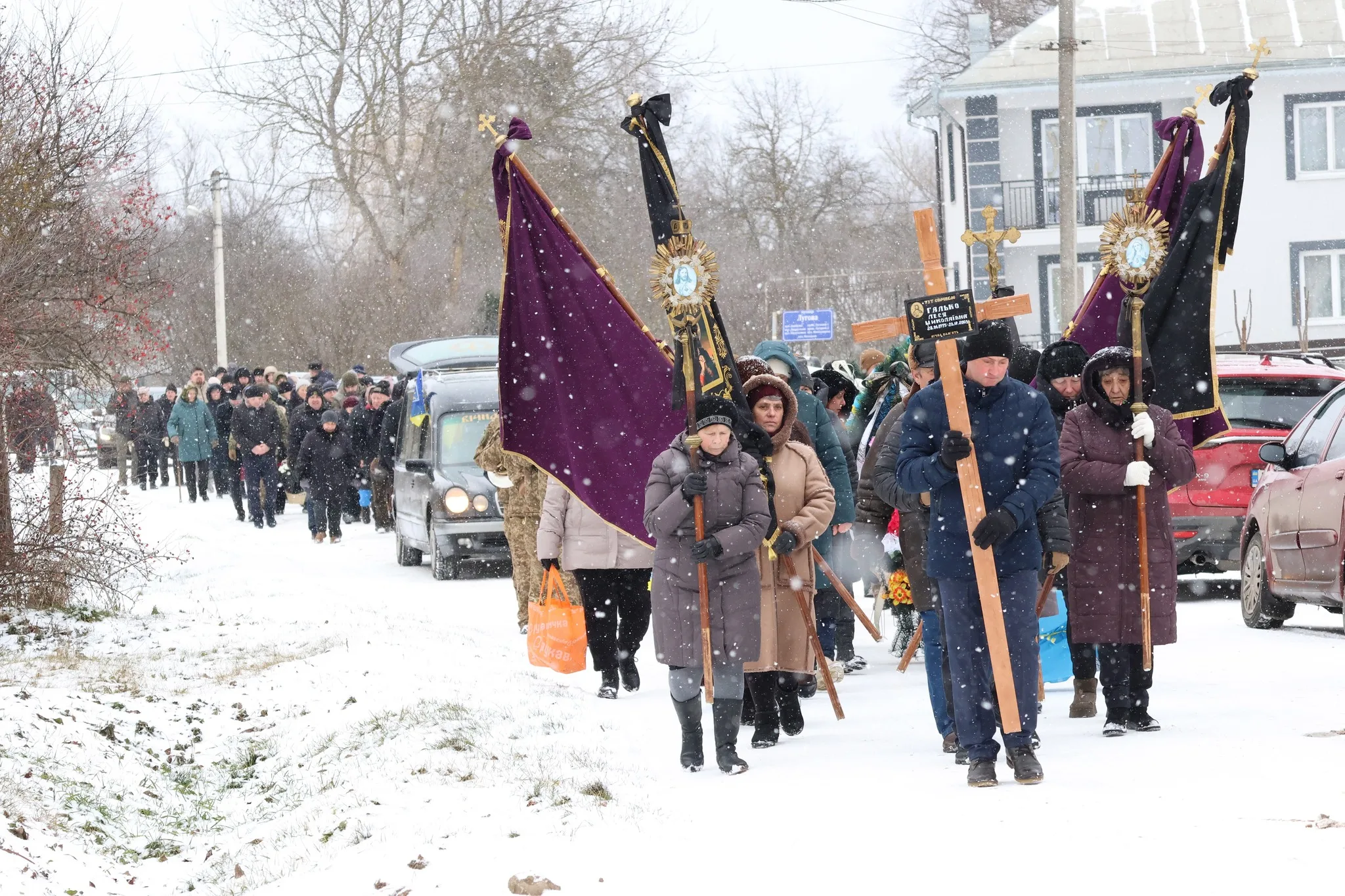 Похоронна процесія йде засніженою вулицею села