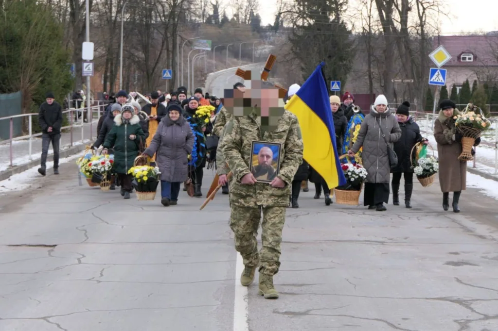 Похоронна процесія з українським прапором і квітами