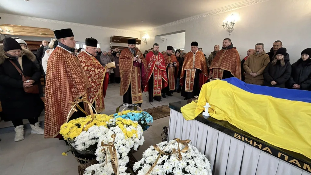 Похоронна церемонія з українським прапором і священниками