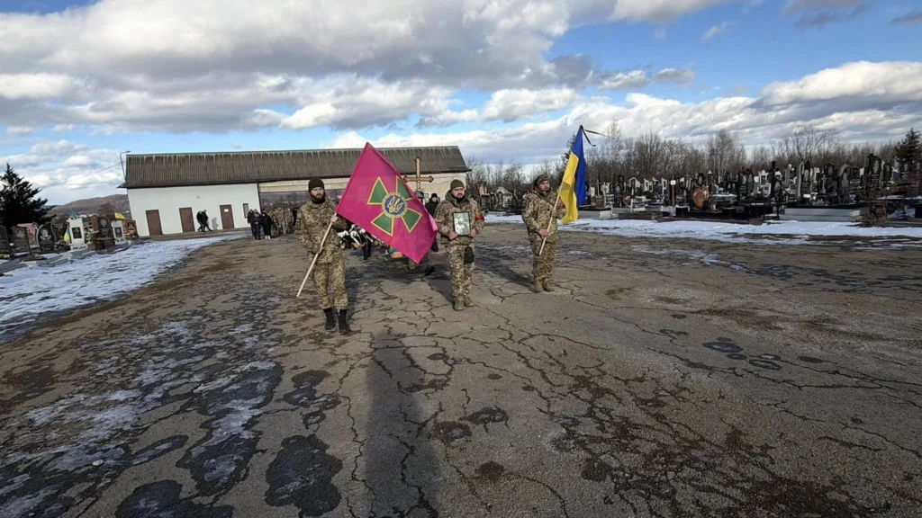 Військові несуть українські прапори на цвинтарі