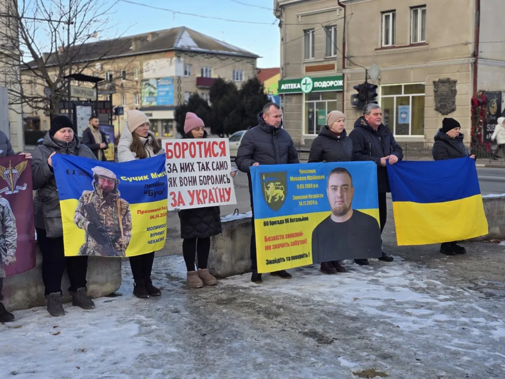 Люди тримають плакати та прапор України на вулиці