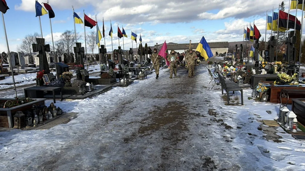 Військові несуть прапори на цвинтарі взимку