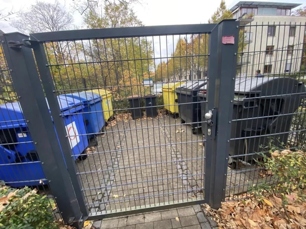 Сміттєві баки за металевими воротами на вулиці