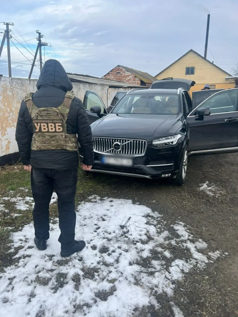 Офіцер стоїть біля чорного позашляховика Volvo