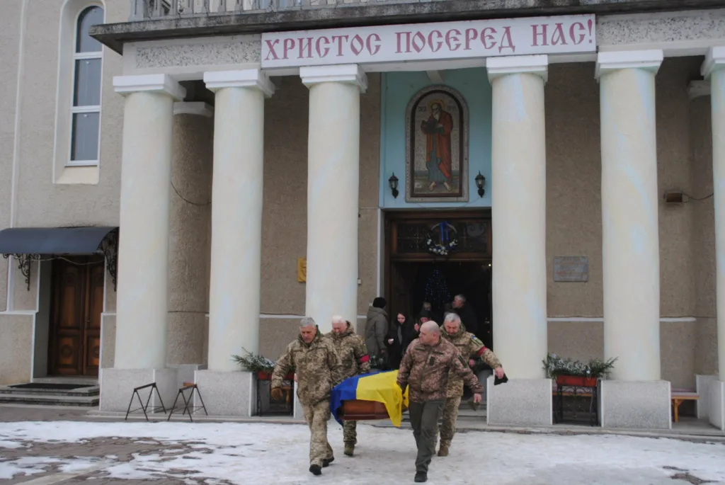 Військові несуть труну з прапором України з церкви