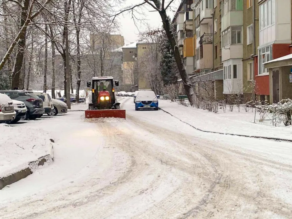 Трактор очищує сніг на дворі житлового будинку