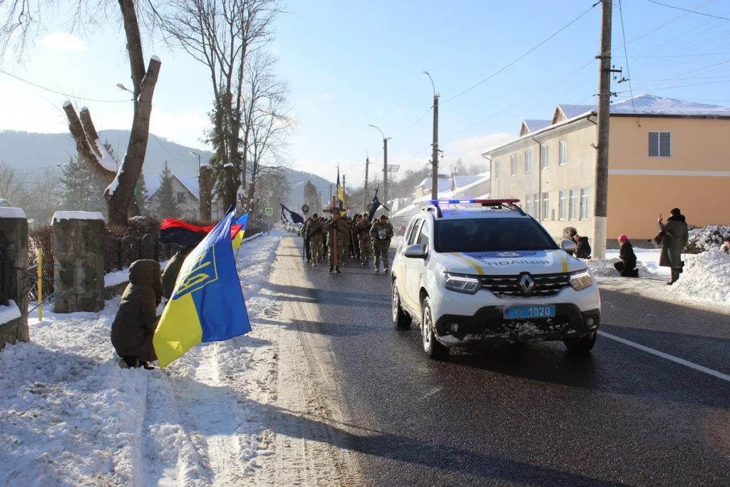 Поліцейський ескорт супроводжує військову ходу зимовою вулицею